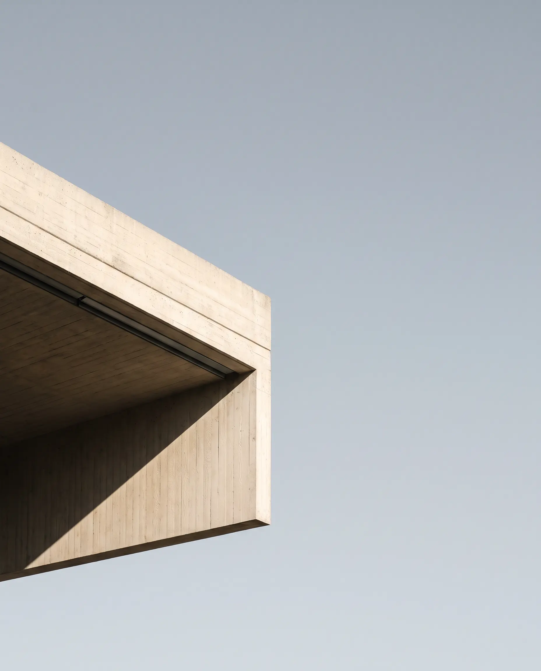The cantilevered corner of the pavilion, soffit in shadow above the water.